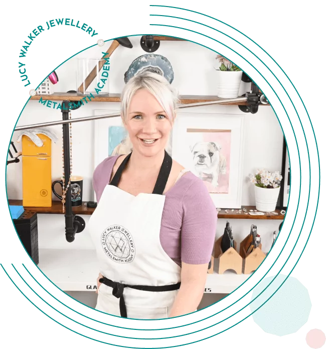 A person in an apron smiles in a workshop with various tools and artworks in the background. From a guide on jewelry making tools.